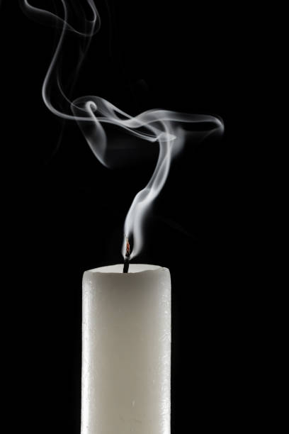 wax candle with burning wick and smoke, isolated on a black background